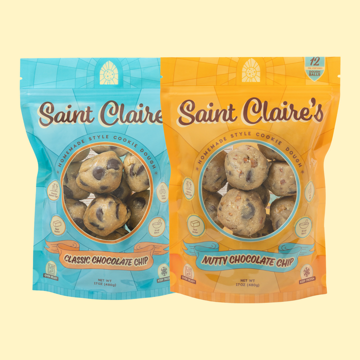 Two packages of Saint Claire's chocolate chip cookie dough, one labeled 'Nutty Chocolate Chip' and the other 'Classic Chocolate Chip'. Each package displays the cookies visible through a transparent window and has the brand's logo.